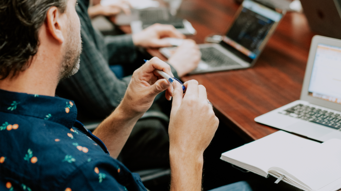 People sitting at board room table with laptops in front of them